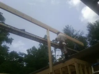 Carpenter setting a ridge beam over a new addition frame — Ice Dam Removal by Roofing Brothers in Sagaponack