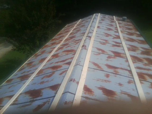 Rusted metal roof panels with new wood purlins before replacement — Storm Damage Roof Repair in Sagaponack by Roofing Brothers