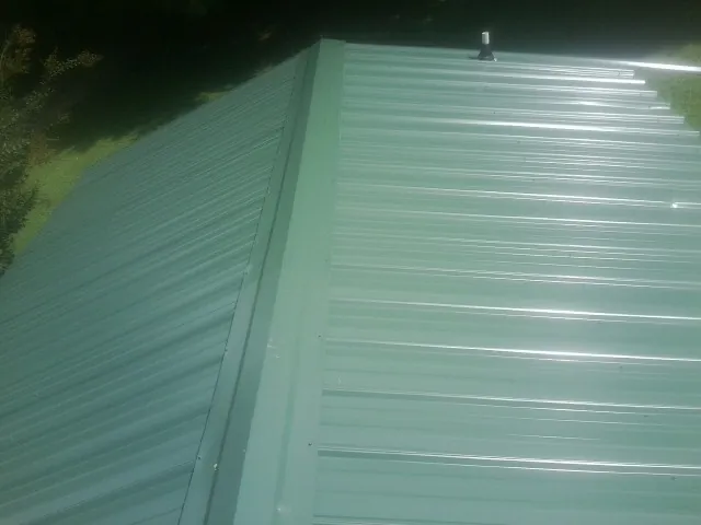 New green metal panels meeting at the ridge of a roof — Flat Roof Repair work by our crew in Sagaponack