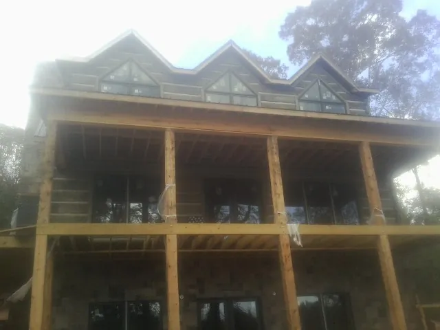 Dormers and porch framing on a large log home under construction — Roof Coating work by our crew in Sagaponack