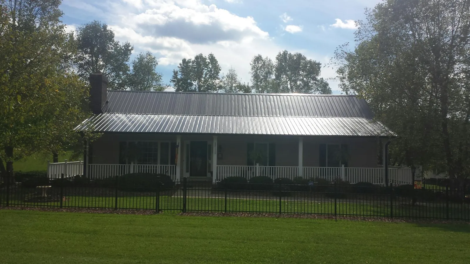 Gray metal roof on a brick ranch with a full width front porch — Gutter Guard Installation work by our crew in Sagaponack
