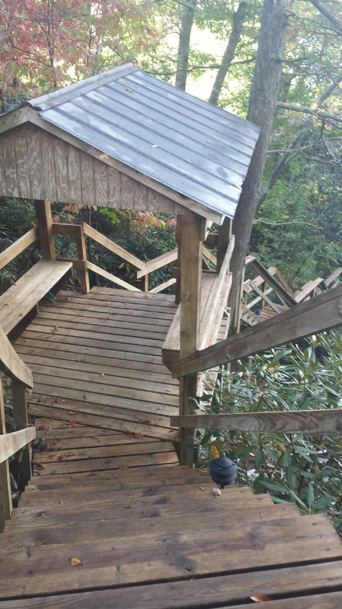 Metal roofed shelter over wooden steps on a wooded walkway — Skylight Repair & Installation work by our crew in Sagaponack