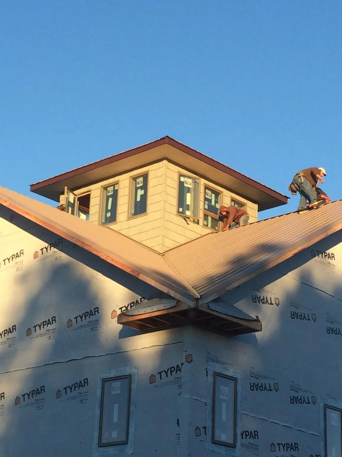 Roofers working around a rooftop cupola on a new metal roof at sunset — Roof Waterproofing in Sagaponack by Roofing Brothers